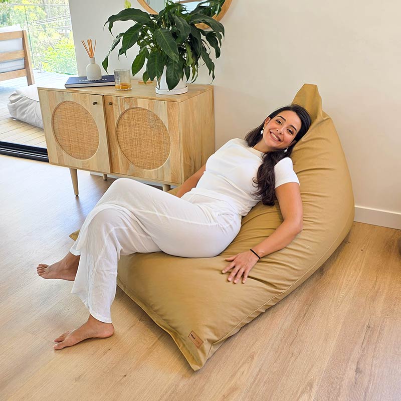 Tan Cotton Canvas Triangle lounge bean bag chair by Mooi Living styled in a modern Australian home with timber flooring, woman sitting.