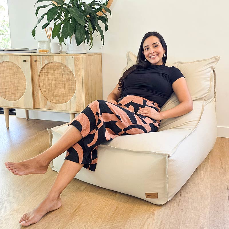 In a contemporary Australian living room, a woman sits on the Mooi Living Single Boss Bean Bag in Natural 100% cotton canvas.