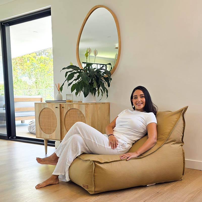 Side view of woman relaxing on the comfortable Tan Single Boss bean bag by Mooi Living in a contemporary setting.
