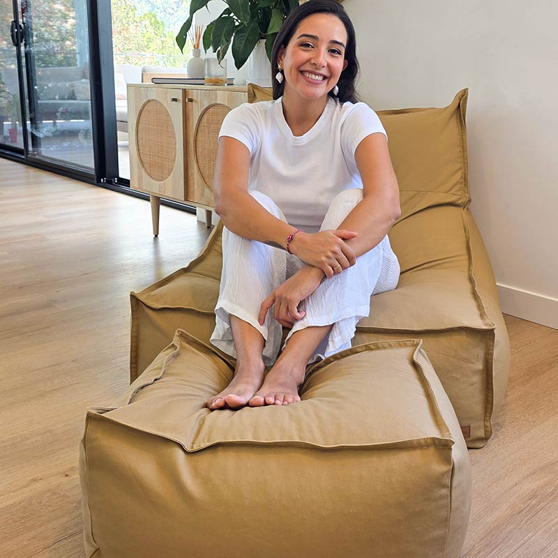 Tan Single Boss Bean Bag by Mooi Living styled with coordinating cotton canvas ottoman in a modern living room. Model sitting up comfortably with feet on the ottoman.