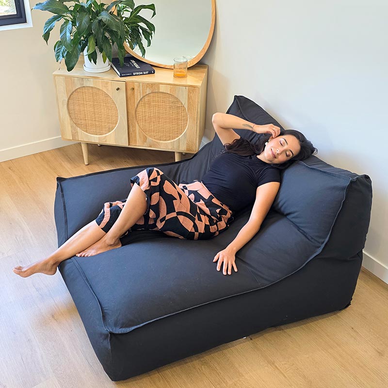 Woman Laying back on the Black Double Boss oversized bean bag chair by Mooi Living with removable cover.