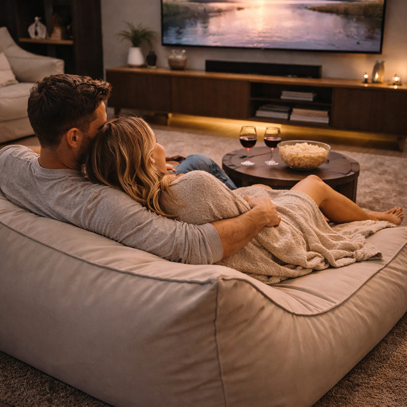Lifestyle Image of Double Boss Lounger indoor bean bag by Mooi Living in Natural Beige with a couple watching TV together in a cozy living room with popcorn and wine.