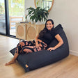 Black Cotton Canvas Triangle lounge beanbag chair by Mooi Living styled in a refined modern interior, woman sitting in a relaxed pose.
