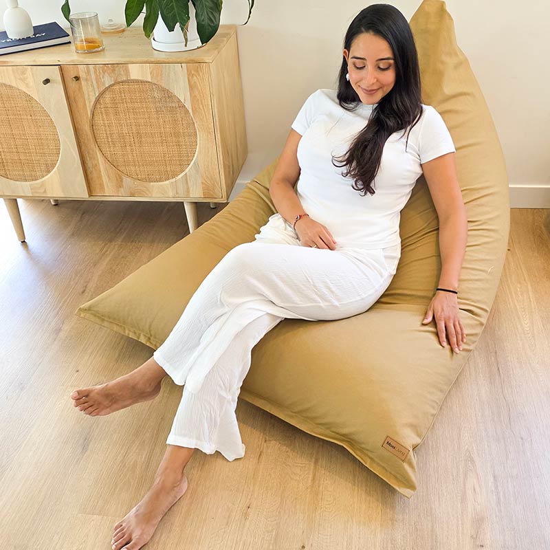 Tan Designer Cotton Canvas Triangle Bean Bag Chair by Mooi Living in a light-filled living room, lady seated.