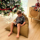 Tan 100% Cotton Canvas Mini Triangles indoor bean bag by Mooi Living in a living room setting with a Christmas Tree, a young boy seated and reading.
