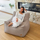 Woman seated on the Taupe Serena bouclé indoor bean bag chair by Mooi Living in a contemporary home interior.