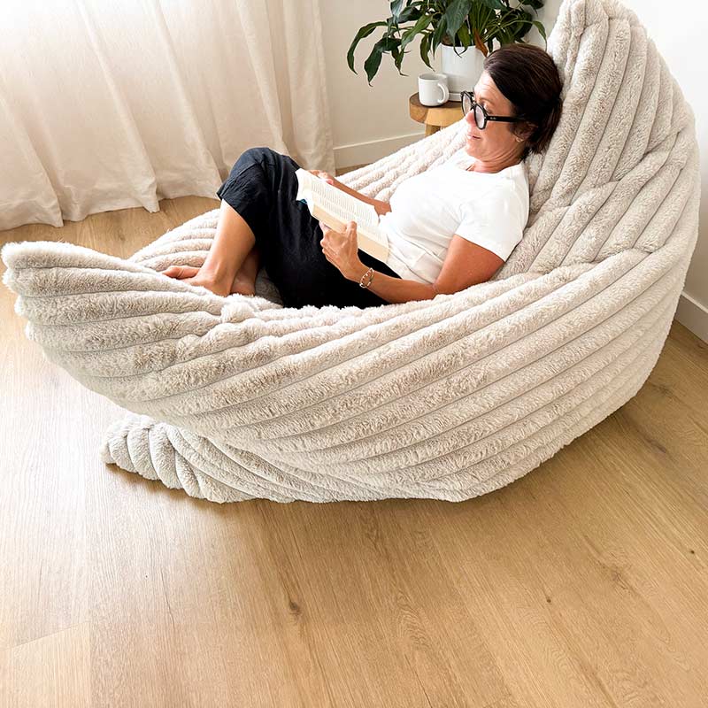The Cloud Bean Bag in Champagne with female model reading a book in a modern living room