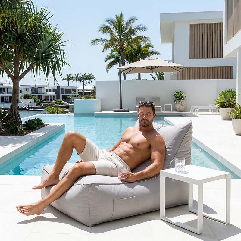 Lifestyle image - Australian resort-style pool area with palm trees, white stone tiles and luxury outdoor setting, Lachlan Bean Bag Lounger placed beside the pool.