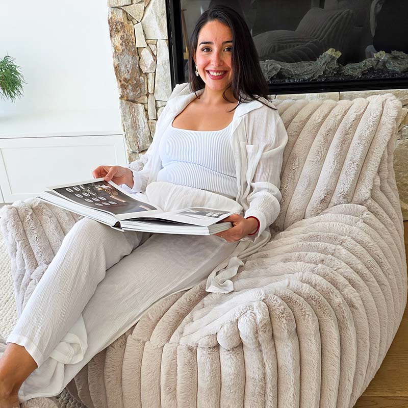 Woman sitting on a Callie Armchair Indoor Bean Bag by Mooi Living in Champagne Corduroy while reading a magazine 