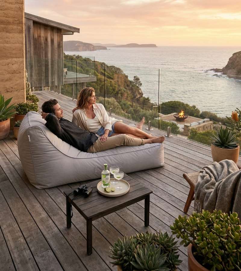 Two people relaxing on an outdoor bean bag by Mooi Living on a deck with ocean view
