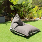 Mooi Living Oyster Black reversible triangle outdoor bean bag on grass, showing its plain side with striped edging, MOREVSTRIBB-BLASTR