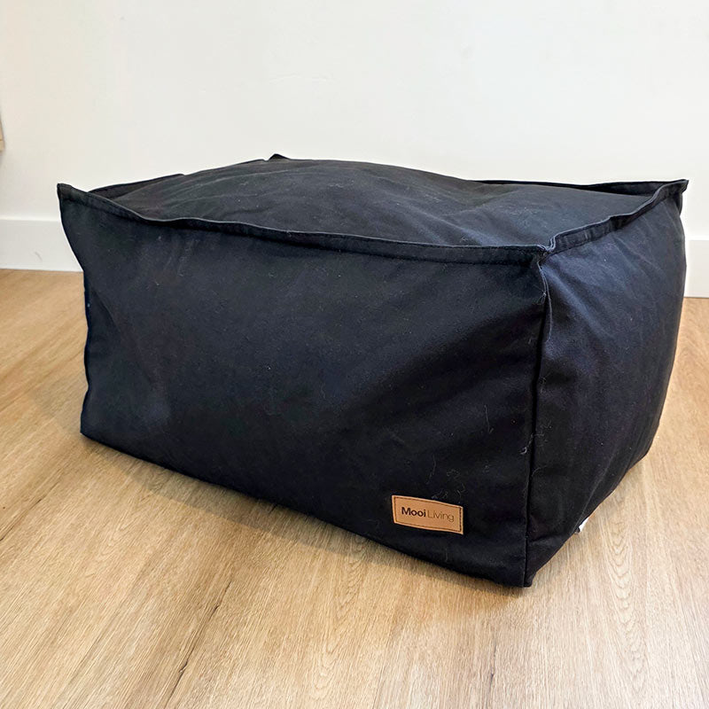 Mooi Living Black cotton canvas ottoman set against a clean interior wall.