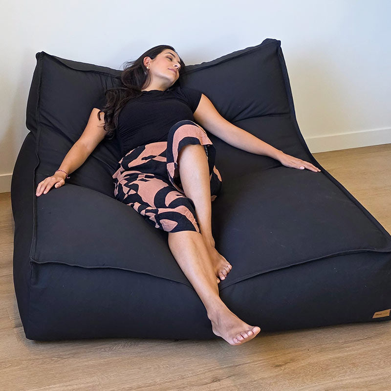 Woman relaxing on the most comfortable Black Double Boss oversized bean bag chair by Mooi Living with removable cover.
