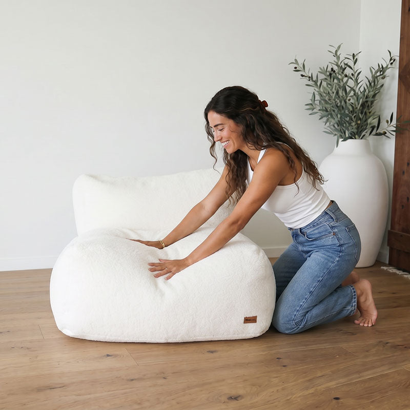 Woman styling the Hallie indoor bean bag chair by Mooi Living in a modern, cozy room with a plant and wooden floor.